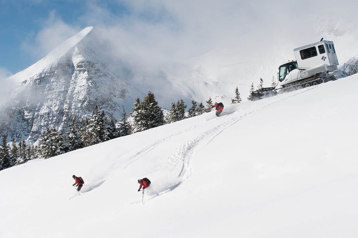 3 skiers descending powder