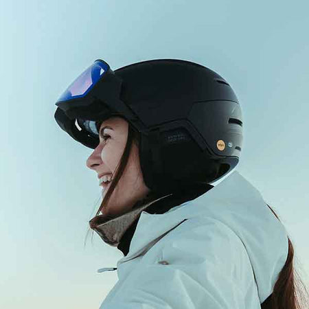 woman smiling on the ski hill wearing a helmet