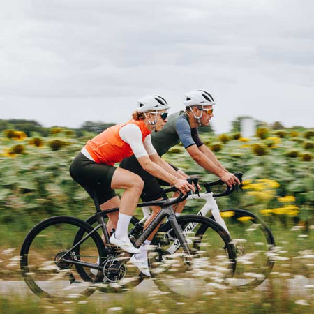 Man and woman cycling beside a sunflower field