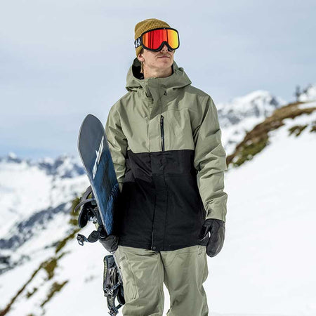 snowboarder walking with mountain in the background