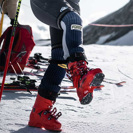 ski racer with race ski boots on lifting one leg up