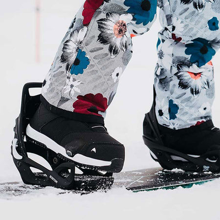 snowboarder stepping into her snowboard bindings