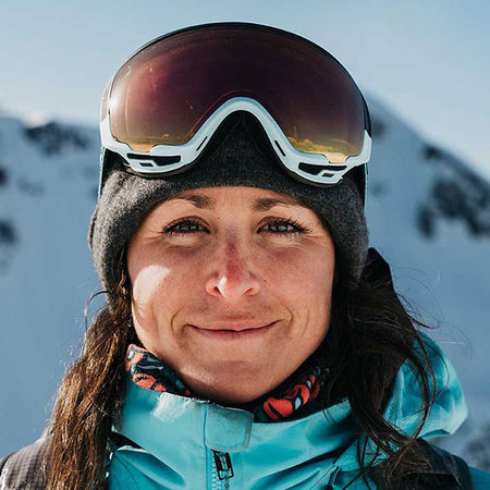female snowboarder smiling with goggles on the top of her head