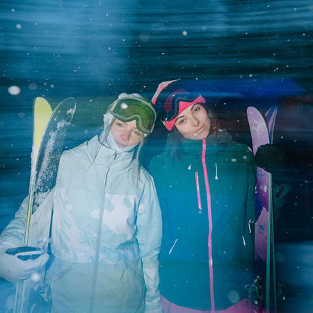 two women standing with their skis